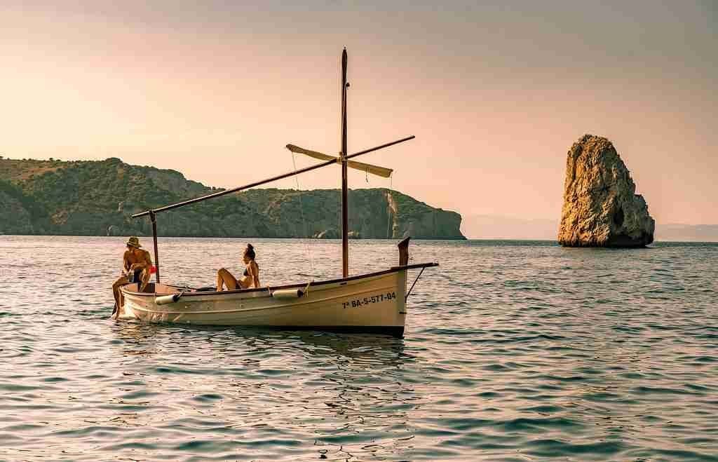 Barque au mouillage devant un rocher, au coucher du soleil
