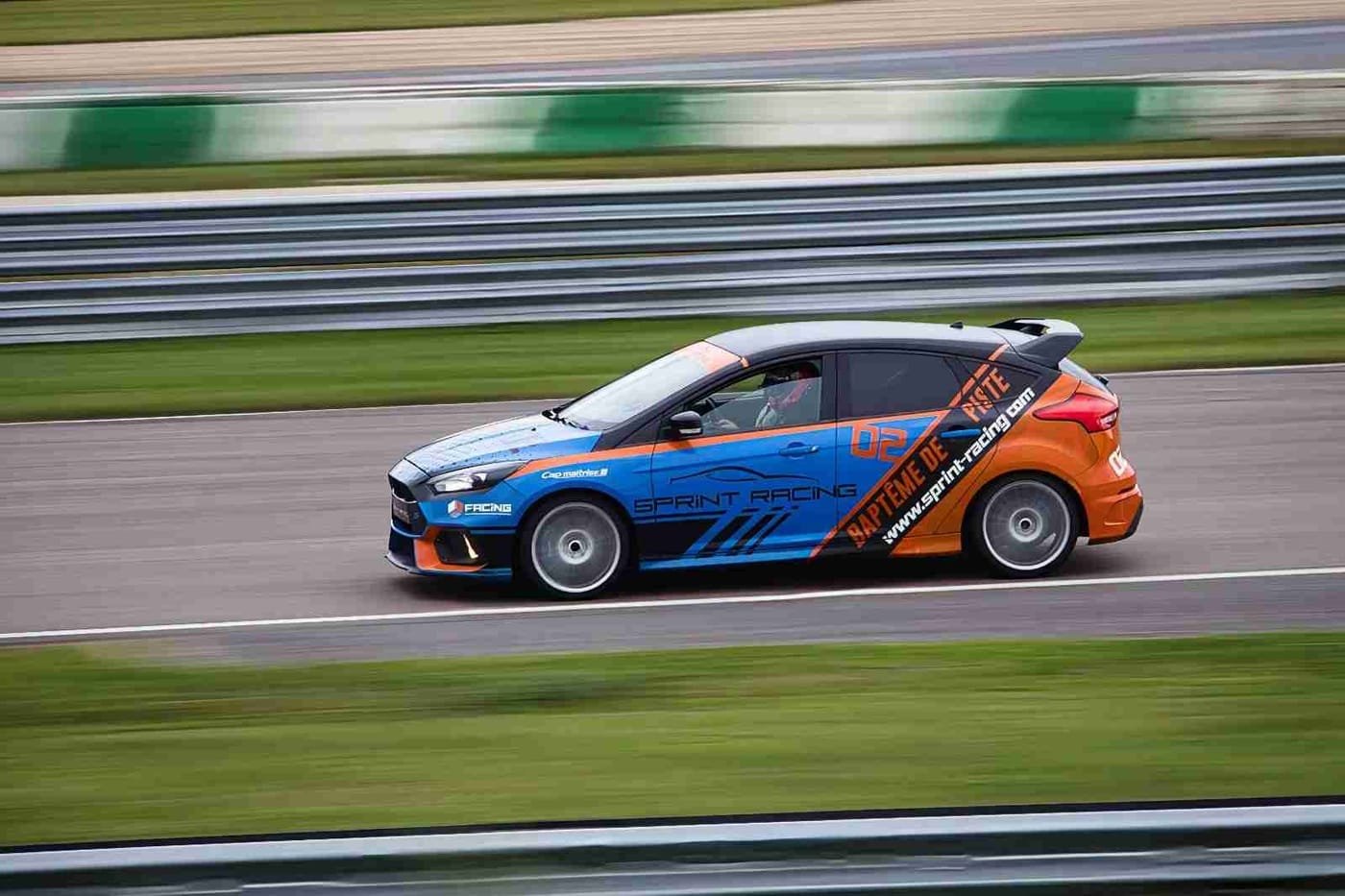 Voiture de course bleue et orange en filé sur circuit