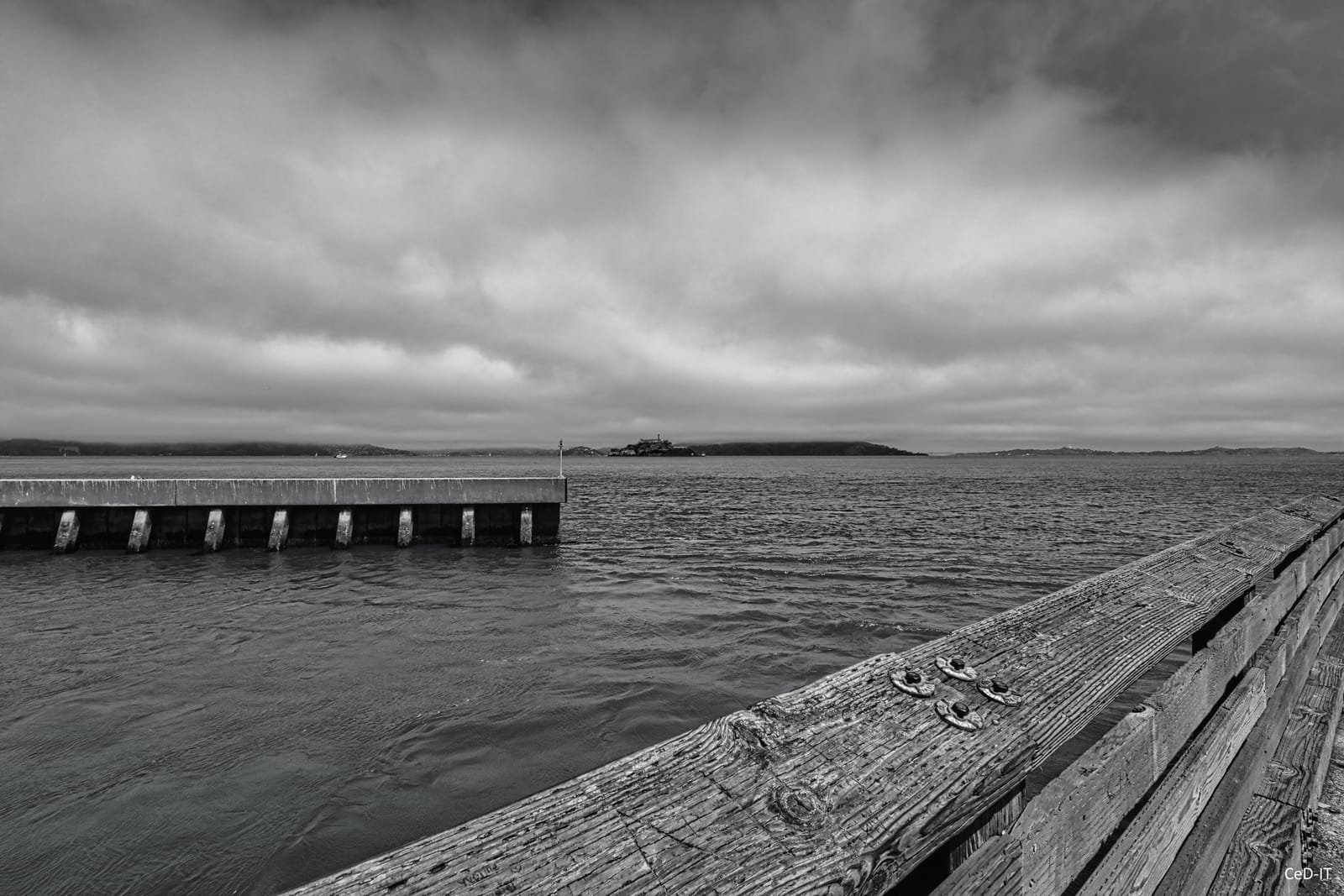 Ponton de bois avançant dans une baie, en noir et blanc