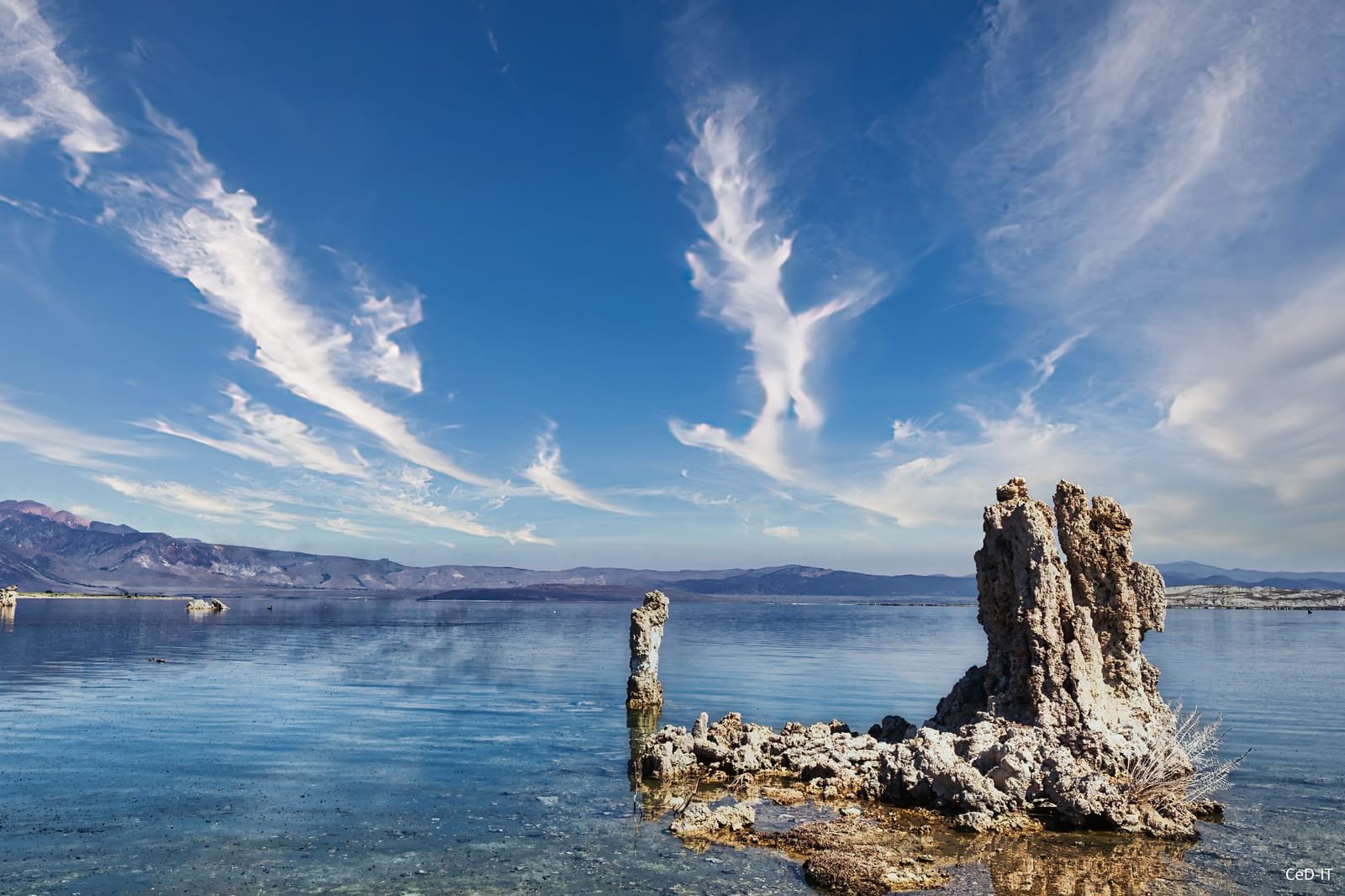 Colonnes de tuf émergeant d’un lac sous un ciel strié de nuages